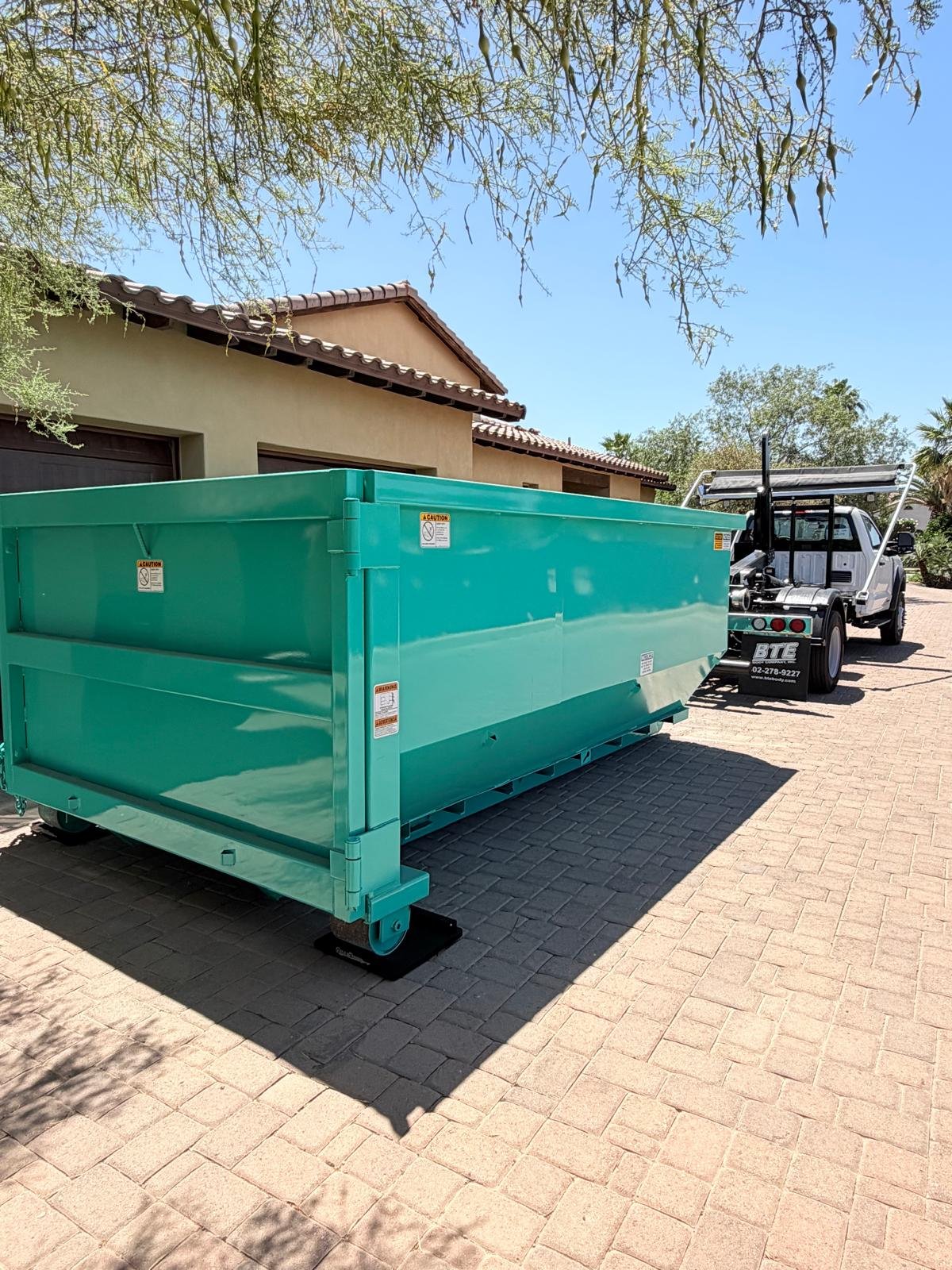 East Valley Bin Co. roll-off truck placing a teal 15-yard dumpster for a roofing tear-off job in the East Valley, Arizona